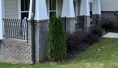 Diamond-pattern porch railing between white columns above a brick foundation