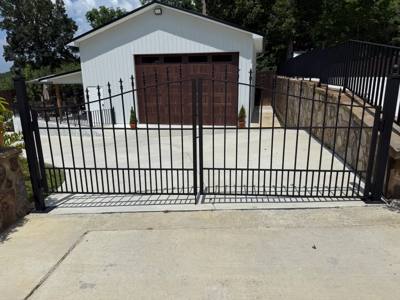 Double black driveway gates in front of a detached garage