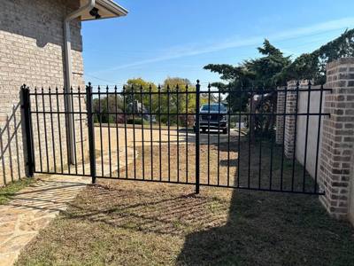 Double black spear-top driveway gates between masonry walls