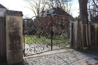 Double driveway gates with elaborate scrollwork between masonry walls