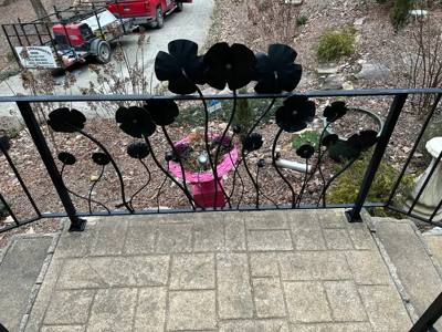 Flower-and-stem railing panel viewed from a paved porch landing