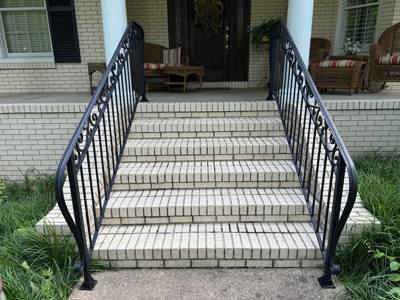 Front view of ornate black scrollwork railings on wide brick steps