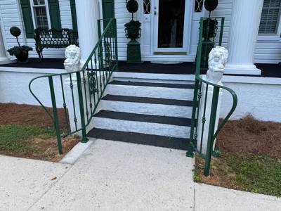 Green handrails with outward-curled ends beside black-and-white entrance steps