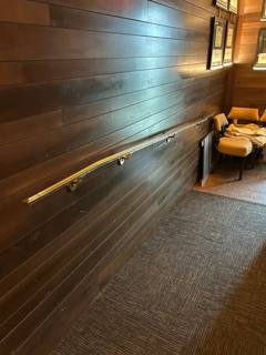 Handrail along a narrow wood-paneled interior passage viewed toward seating