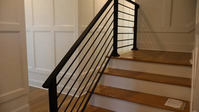 Horizontal-bar black railing beside a light wood interior staircase