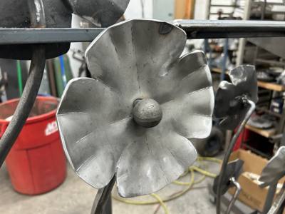 Large textured flower blossom on a curved metal stem in the workshop