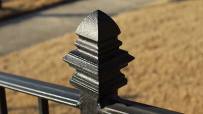 Layered pyramid finial atop a black railing post