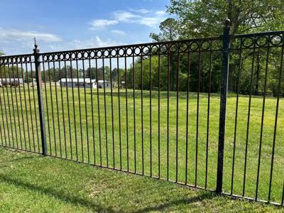Long black lawn fence with a row of circular ornaments beneath the top rail