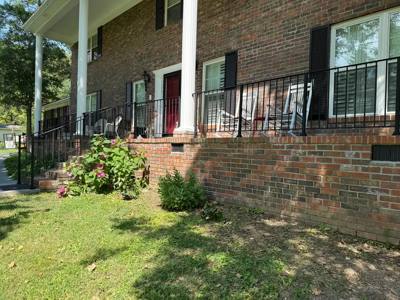 Long black railing across a brick porch beneath white columns