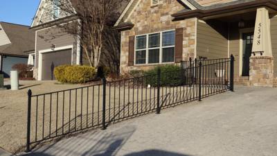 Long black railing following a sloped concrete entrance walkway