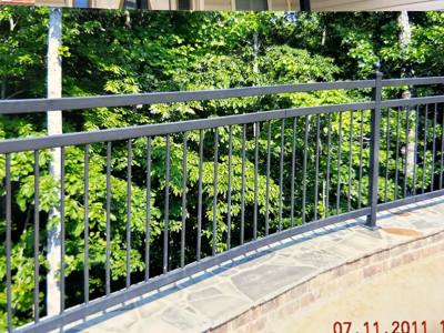 Long black railing with small decorative collars above a stone terrace