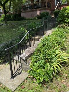 Long garden stairway bordered by black vertical-bar railings