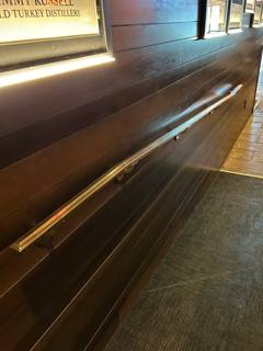 Long polished horizontal handrail mounted along a brick interior wall