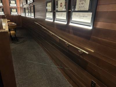 Long wall-mounted handrail beneath framed signs in a wood-paneled interior