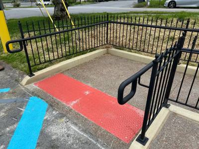 Loop-ended black handrails around a paved ramp entrance