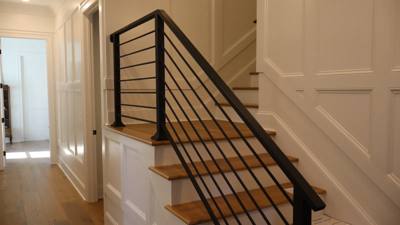 Modern horizontal-bar stair railing against white paneled walls