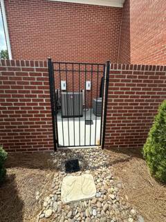 Narrow black spear-top gate between brick walls