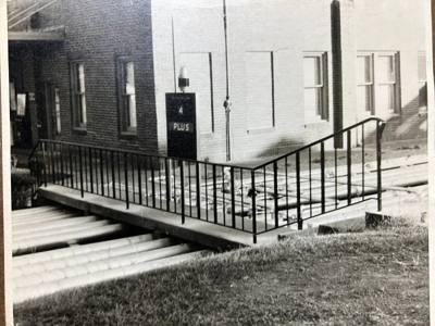 Older black-and-white photograph of a railing around an entrance ramp