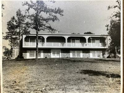 Older black-and-white photograph of a two-story porch with repeated arched supports