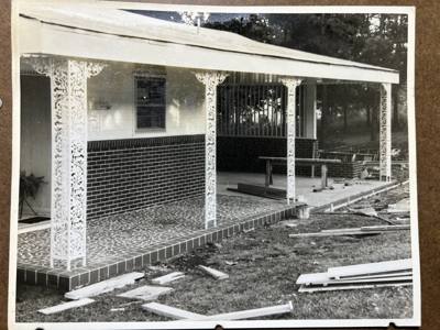 Older photograph of ornamental porch posts along an unfinished front walk