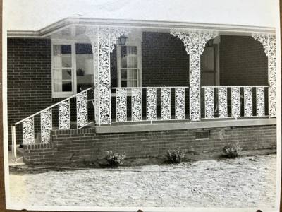 Older photograph of white ornamental posts and railings on a covered porch