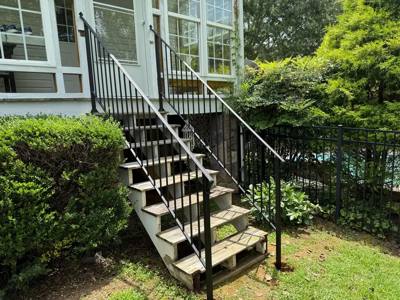 Open exterior staircase with black railings beside a glazed sunroom
