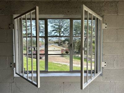 Open white security window grilles on a masonry wall
