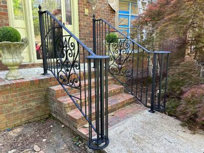 Ornate black scroll panels framing brick steps beneath a green door