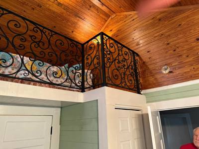 Ornate black scrollwork railing turning around an upper landing