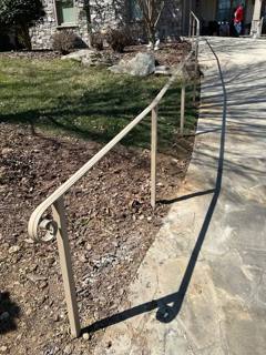 Pale handrail with a curled end following a curved garden path
