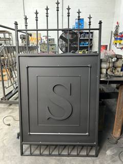 Pedestrian gate with an inset letter S and spear-top ornament in the workshop