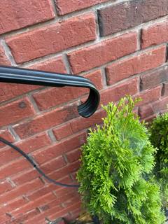Rounded black handrail return beside a red-brick wall
