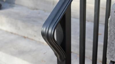 Rounded return end on a black railing top rail