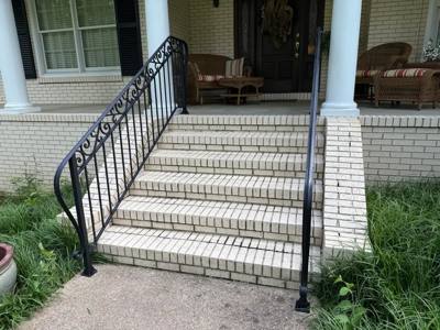 Scroll-accent black handrails beside wide white-brick porch stairs