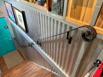 Scroll-ended wall handrail overlooking a wooden interior staircase