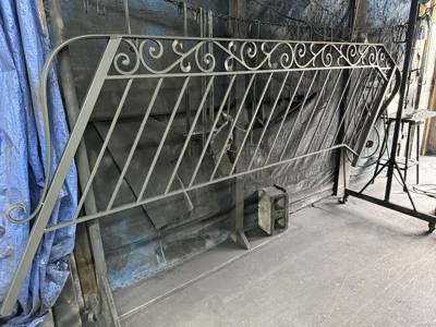 Scroll-topped decorative railing panel leaning upright in the workshop