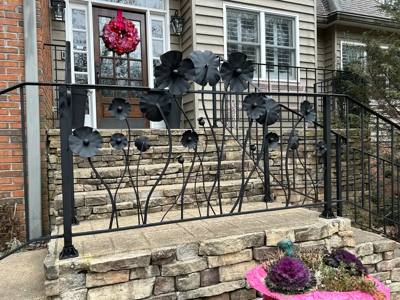 Sculpted black metal flowers forming a decorative porch railing panel