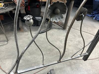 Sculpted flower stems and blossoms in an unfinished metal railing panel