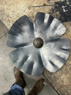 Sculpted metal flower with rippled petals on a workshop bench