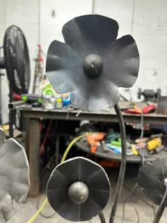 Sculpted metal flowers on tall stems in the fabrication workshop