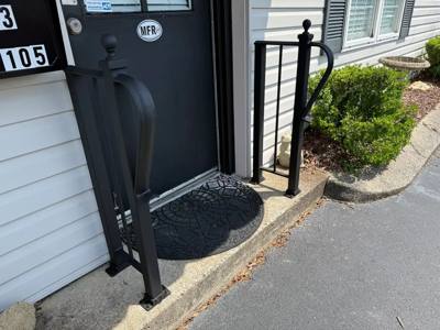 Short black handrail with a looped end beside a narrow doorway