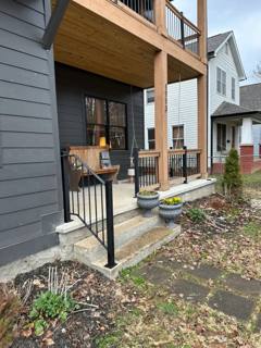 Short black railings beside steps to a timber-post covered porch