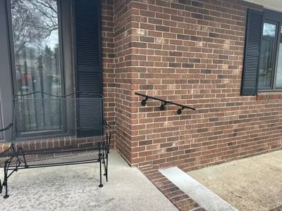 Short black wall handrail beside a brick entrance