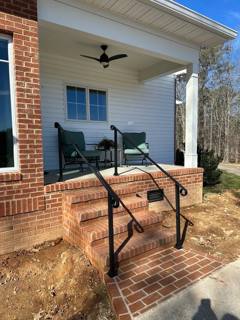 Side view of black handrails beside a tall brick porch and patio chair