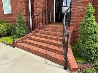 Side view of black handrails on wide red brick entry stairs