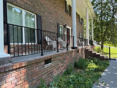 Side view of black picket porch railing above a brick foundation