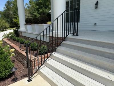 Side view of black picket stair railing beside white concrete steps