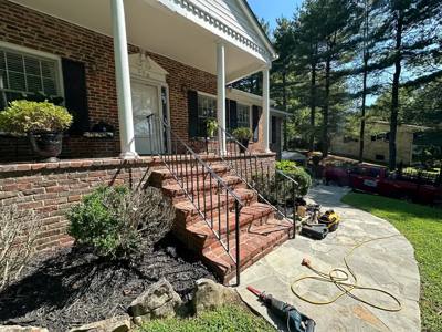 Side view of black stair handrails beside a raised brick porch