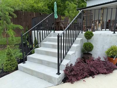 Side view of black stair railings and decorative balusters above a garden bed
