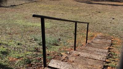 Simple black handrail alongside a short outdoor stone path